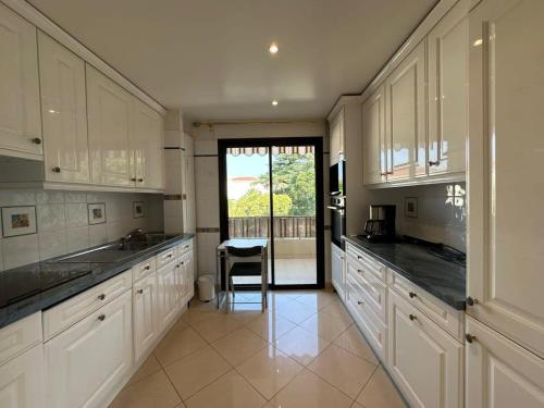 - une cuisine avec des placards blancs et une chaise dans l'établissement A003-Magnifique appartement proche du centre de Cannes, à Cannes