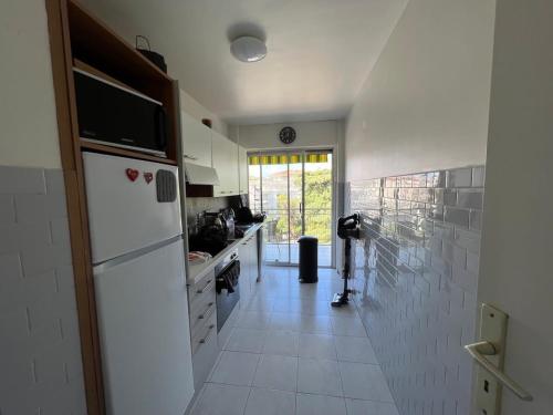 Il comprend une cuisine dotée d'un réfrigérateur blanc et de carrelage blanc. dans l'établissement B049-Appartement lumineux à deux pas de la Croisette, à Cannes