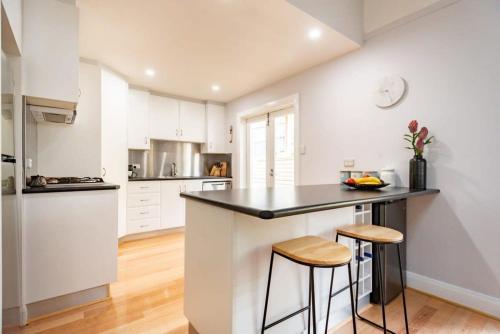 a kitchen with white cabinets and a black counter top at Monte-Vista: Minutes to the City Views & Parking in Newstead