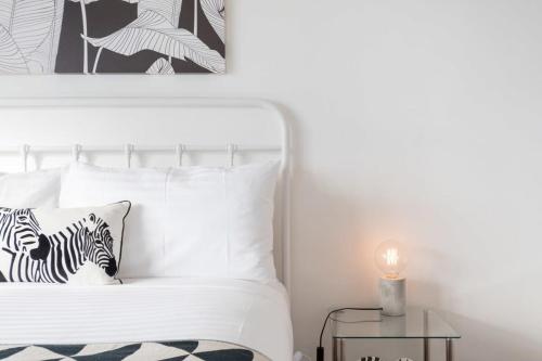 a white bed with a zebra pillow and a table at Monte-Vista: Minutes to the City Views & Parking in Newstead