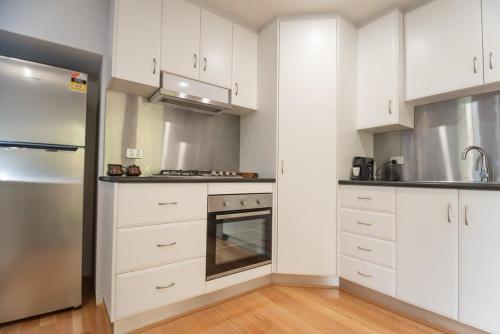 a kitchen with white cabinets and a stainless steel refrigerator at Monte-Vista: Minutes to the City Views & Parking in Newstead