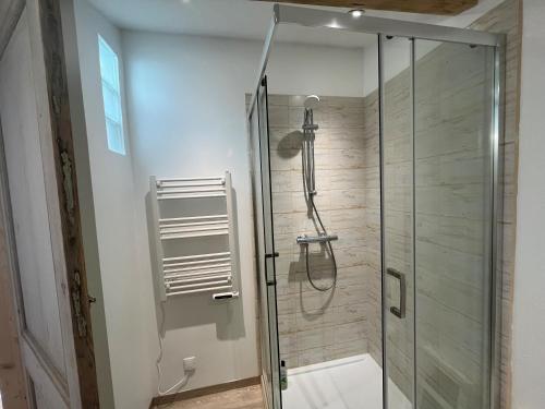 une douche avec une porte vitrée dans une salle de bain dans l'établissement Le Cottage, à Foussignac