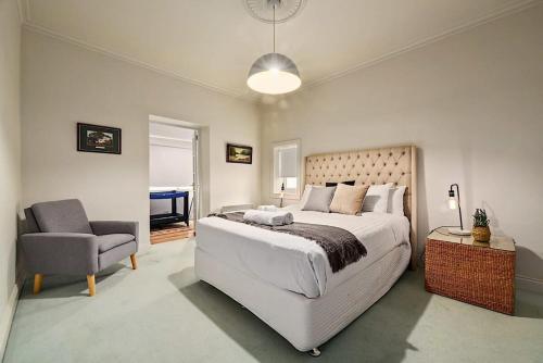 um quarto com uma cama grande e uma cadeira em Blackwood Tree Cottage Heritage Listed Evandale em Evandale