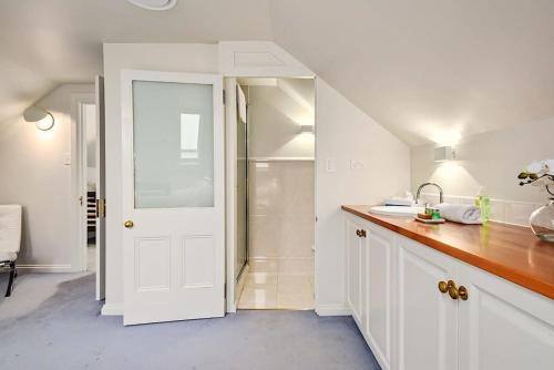 uma cozinha branca com um lavatório e um chuveiro em Blackwood Tree Cottage Heritage Listed Evandale em Evandale