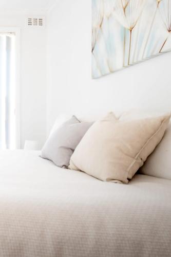 a white bed with white pillows on it at Near the CBD Perfect for Large Groups & Parking in Kings Meadows