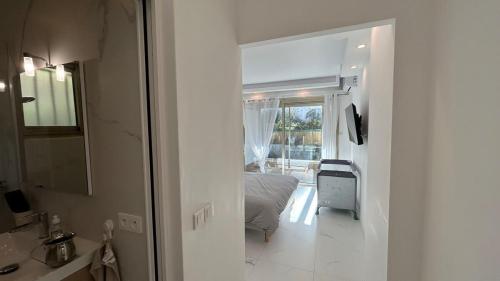 Cette chambre blanche comprend un lit et une salle de bains. dans l'établissement A010-Superbe appartement refait à neuf proche Croisette, à Cannes