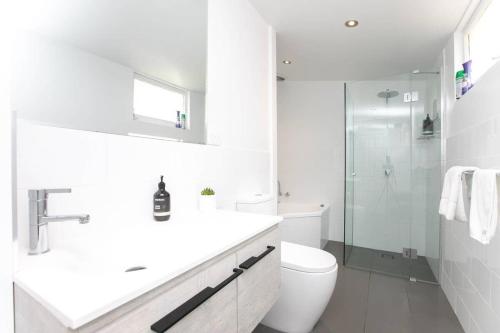 a white bathroom with a toilet and a sink at East Launceston with Views and Parking in Kings Park