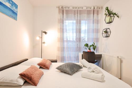 a bedroom with a white bed with pillows and a window at Luma Luxury Apartment with Jacuzzi in Zadar