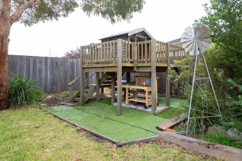 a wooden tree house with a windmill in a yard at Swift's at Stieglitz in St Helens