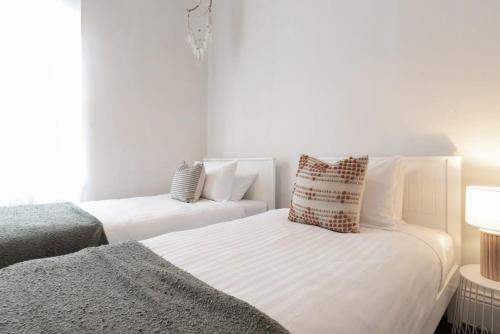 Un dormitorio blanco con dos camas y un sofá. en Charming Little Home Close To The City w Parking And Wifi, en Kings Park
