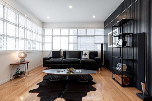 a living room with a black couch and a table at Inner City Living in Launceston