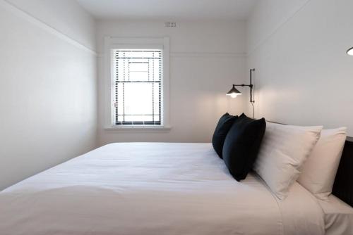 a bedroom with a large white bed with black pillows at Inner City Living in Launceston