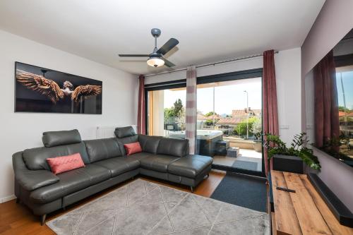 a living room with a black leather couch at Luma Luxury Apartment with Jacuzzi in Zadar