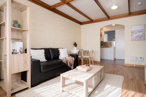 uma sala de estar com um sofá preto e uma mesa em Cosy & Convenient: WiFi & Parking em Kings Park