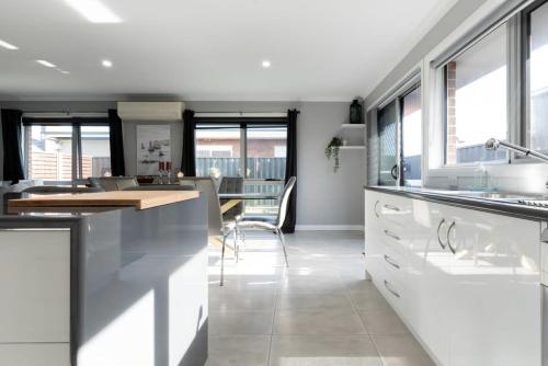 a kitchen with white cabinets and a dining room at Devonport Delight Close To Ferry Terminal Dog Friendly "Happy Tails" in Devonport