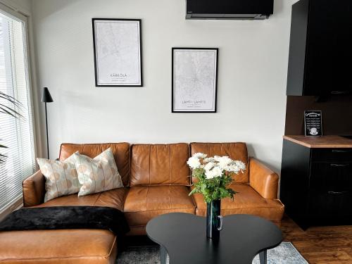 ein Wohnzimmer mit einem braunen Ledersofa und einem Tisch in der Unterkunft Modern & Stylish 2BR Apartment with Sauna, Terrace and Free Private Parking in Lahti