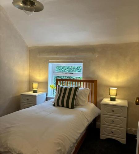 a bedroom with a bed with two night stands and a window at Rosie Cottage in Ashbourne