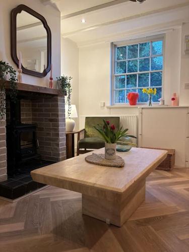 a living room with a table and a fireplace at Rosie Cottage in Ashbourne