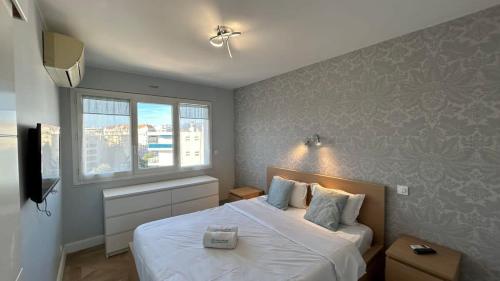 une chambre avec un grand lit blanc avec une fenêtre dans l'établissement B018-Bright apartment with balcony - Cannes Croisette, à Cannes
