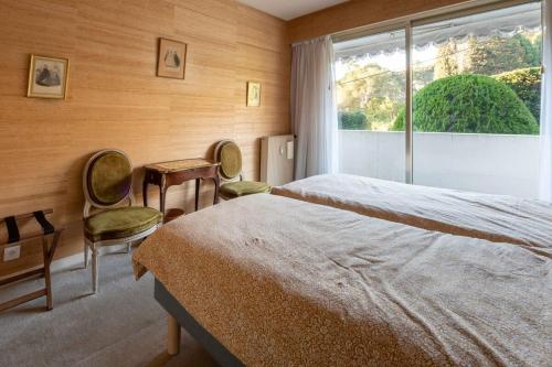 une chambre avec un lit et deux chaises et une fenêtre dans l'établissement A081-Cannes Appartement avec terrasse au calme, à Cannes