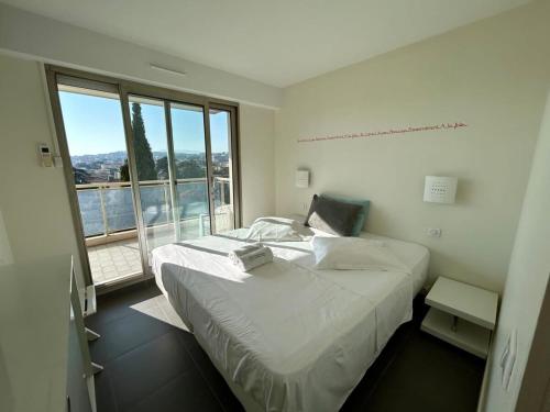 een slaapkamer met een groot bed en een groot raam bij A013-Apt vue mer avec piscine et terrasse in Cannes