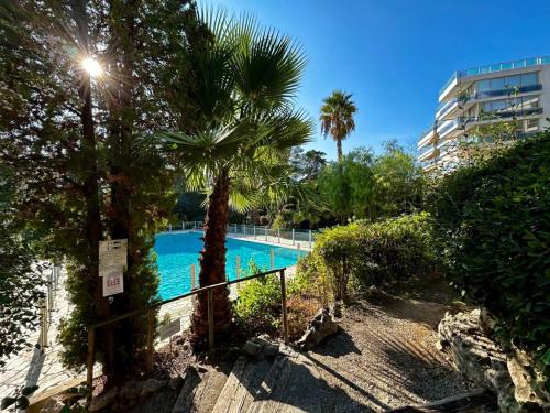 une piscine avec des palmiers et un bâtiment dans l'établissement A013-Apt vue mer avec piscine et terrasse, à Cannes