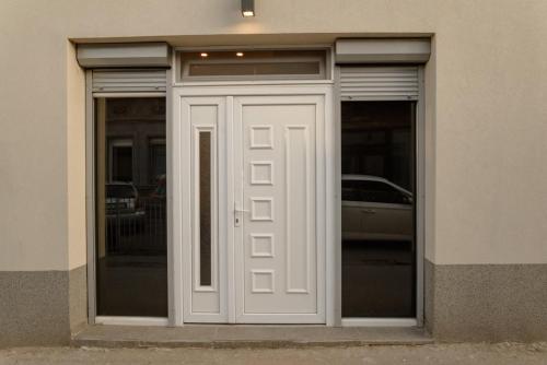 Una puerta blanca de un edificio con un coche en él en Sen's Studio en Leskovac