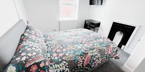 Cozy Room in Modern House near Nottingham في نوتينغهام: غرفة نوم مع سرير وبطانية مزهرة