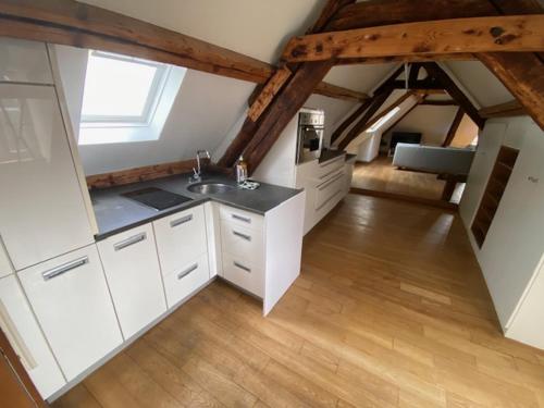 - une cuisine mansardée avec des placards blancs et un évier dans l'établissement APPARTEMENT VICTOR HUGO, à Amiens