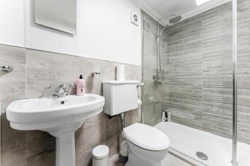 a white bathroom with a toilet and a sink at Luxurious Park District Duplex Apartment in Glasgow