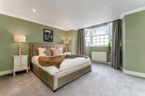 a bedroom with a large bed and a window at Luxurious Park District Duplex Apartment in Glasgow