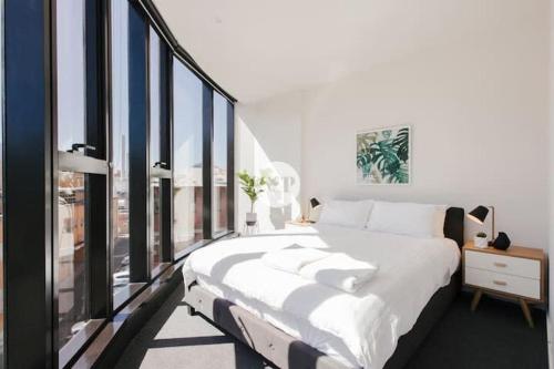 una camera da letto con un letto grande e grandi finestre di St Kilda Rd LVL4 2BDR2BATHR WIFI Albert Park a Melbourne