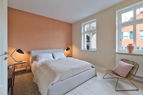 een slaapkamer met een bed en een stoel en 2 ramen bij Apartment Mosel-Sauna-Terrasse in Ürzig