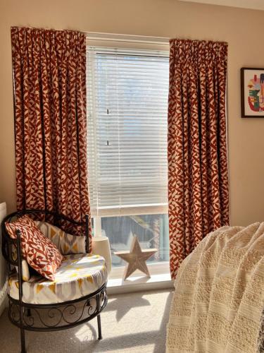 a bedroom with a chair and a window with curtains at Chocolate Quarter Townhouse in Keynsham