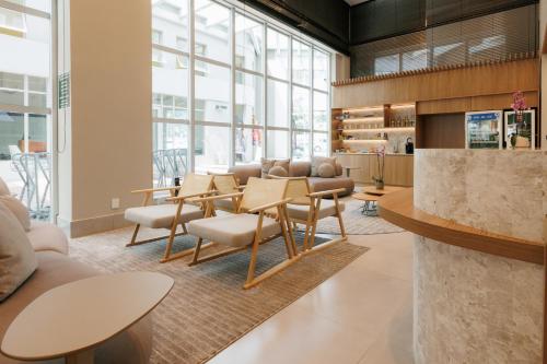 a lobby with chairs and tables and windows at eSuites Belo Horizonte Minascasa in Belo Horizonte