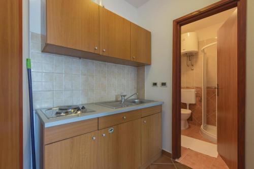 een keuken met een wastafel en een badkamer met een toilet bij Apartments Riva Medulin in Medulin