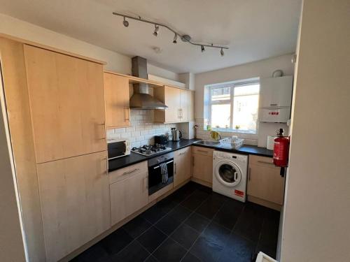 a kitchen with wooden cabinets and a washer and dryer at Shoreditch London - Lovely Two-Bedroom Apartment in London