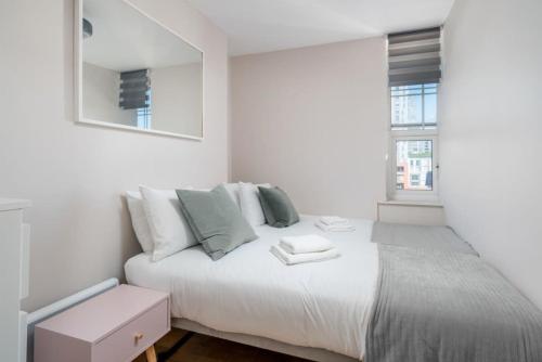 a white bedroom with a bed and a mirror at City of London Lovely Two Bedroom Apartment in London