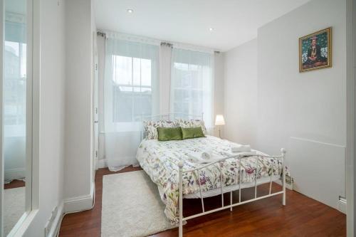 a white bedroom with a bed and a window at TruStay Apartments London Brick Lane in London