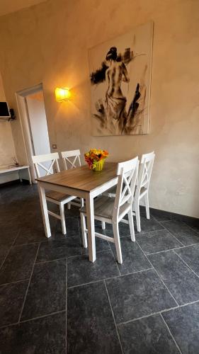 a dining room table with white chairs and a painting at Borgo di Santa Barbara in Santa Domenica