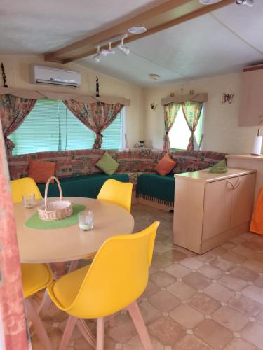 a living room with a table and yellow chairs at Mobil home Camping Bleu Marine in Sérignan