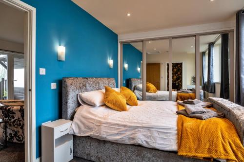 Schlafzimmer mit blauen Wänden und einem Bett mit gelben Kissen in der Unterkunft Finest Retreats - Classroom Lodge - Two in Lifton