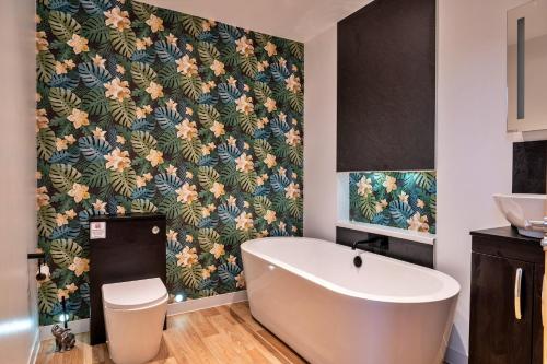 uma casa de banho com uma banheira e um papel de parede florido em Finest Retreats - Classroom Lodge - Two em Lifton