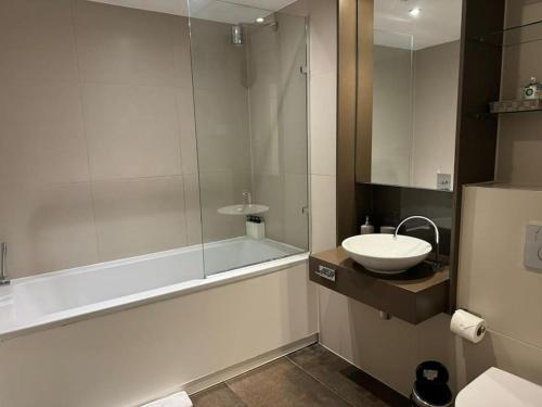 a bathroom with a tub and a sink and a shower at Modern apartment w/ canal view in London