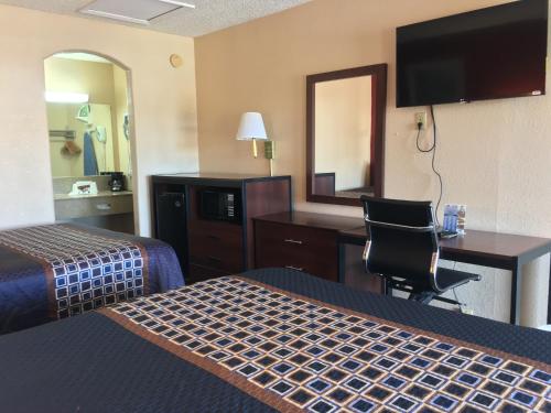 a hotel room with two beds and a desk and a mirror at Americas Best Value Inn-Near NRG Park/Medical Center in Houston