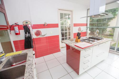 a red and white kitchen with a sink and a stove at Loft con sala, desayunador y baño in Lomas de Angelopolis
