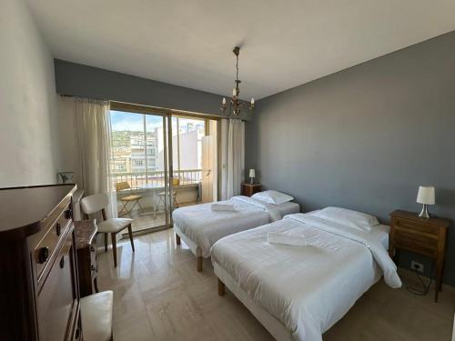 - une chambre avec 2 lits, une table et un balcon dans l'établissement A017-Charmant 2 pièces à 200M de la Croisette, à Cannes