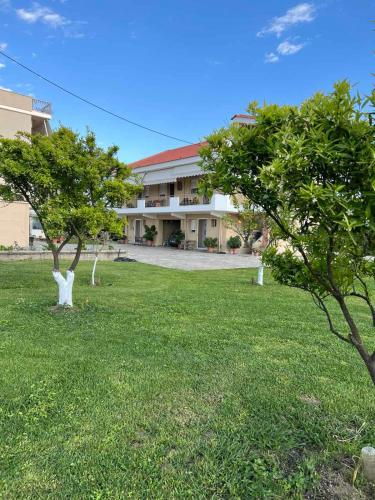 a building with two trees in front of a yard at Flo's Apartments in Mesolongion
