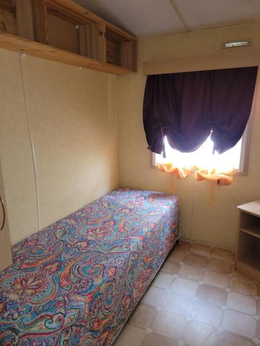 a bed in a small room with a window at Mobil home Camping Bleu Marine in Sérignan