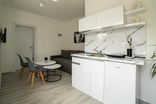 a kitchen with white cabinets and a table and a couch at Fox Apartment in Gevgelija